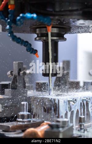 a process of cnc vertical drilling with liquid coolant flow, close-up with selective focus Stock Photo