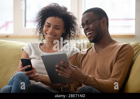 Laughing african american man and woman couple looking at smartphone Stock Photo