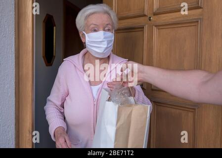 Senior woman gets shopping bag from neighborhood assistance Stock Photo