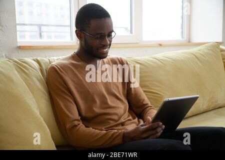 Smiling African American man holding and using tablet. Stock Photo