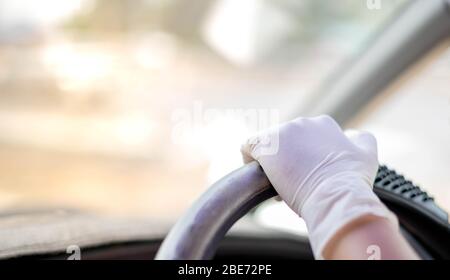 Female hand wearing sugical gloves and Hand holding the car steering wheel  for protection and prevent Coronavirus (Covid-19) pandemic world crisis, w Stock Photo