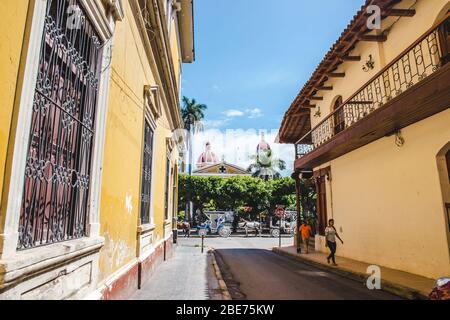 Side street leading to the yellow colonial architecture of the main plaza, Parque Central de Granada, Nicaragua Stock Photo