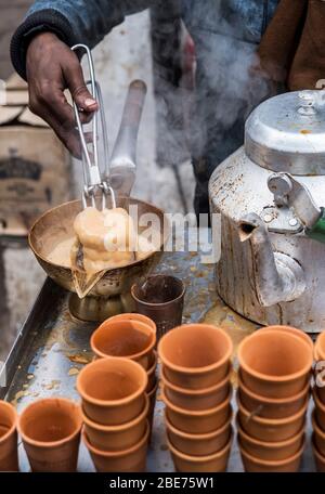 tandoori chai in India - spicy milk tea being poured over a hot terracotta cup straight from tandoori oven Stock Photo