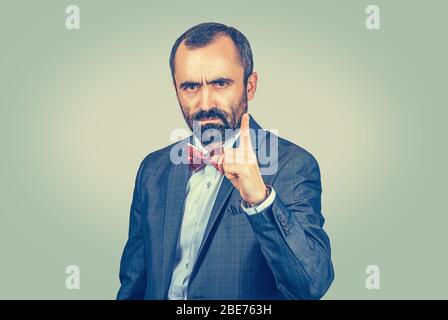 Closeup portrait headshot confident angry serious young man, business man showing index finger for admonition isolated light green background. Multicu Stock Photo