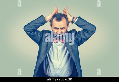 businessman holding hands on head in frustration, stressed man upset frustrated isolated on light green wall background with yellow gradient. Negative Stock Photo