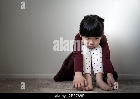 Lonely sad little girl holding her knees Stock Photo