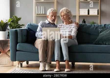 Mature man and woman using laptop together, looking at screen Stock Photo