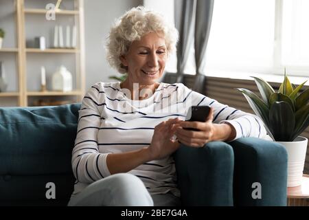 Happy smiling older woman using phone, looking at screen Stock Photo