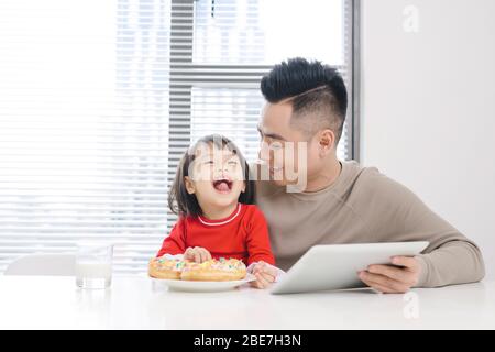 Young dad and his daughter eating pizza and using ipad. Stock Photo