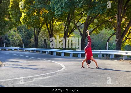 Fit man in red costume doing yoga on the asphalt road in Almaty, Kazakhstan Stock Photo