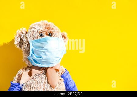 Coronavirus covid-19 and pollution protection concept. teddy bear doll wearing mask and protective gloves on yellow background, copy space Stock Photo