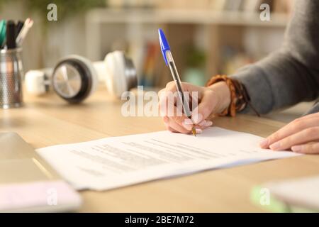 Close up of student girl hands signing contract document siting on a desk at home Stock Photo