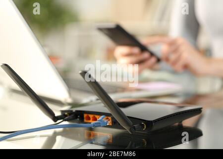 Close up of woman hands using multiple devices with broadband router on foreground Stock Photo