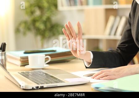 Close up of entrepreneur woman hands waving greeting on videocall on laptop webcam sitting on a desk at home Stock Photo