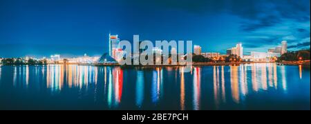 Minsk, Belarus. Panorama With Residential House Near Pobediteley Avenue And Svisloch River. Summer Evening, Night Lights Illumination Reflected in Wat Stock Photo