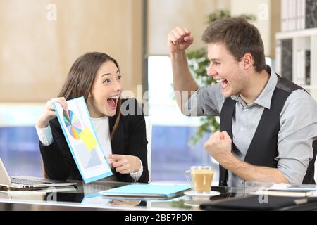 Happy executives celebrating good results with graph report on a desk at the office Stock Photo