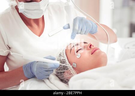 Using new equipment. Close up of professional beauty expert using new equipment for deep facial cleansing Stock Photo
