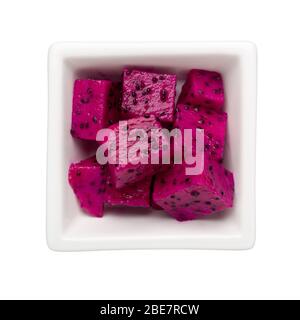 Pieces of red dragonfruit in a square bowl isolated on white background; Stock Photo
