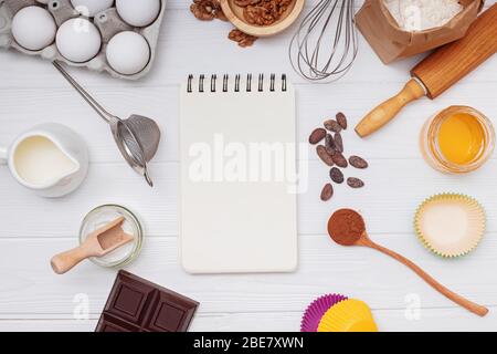Blank paper notepad with place for text and bakery ingredients and utensils on white table Stock Photo