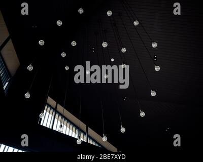 Modern ceiling lights ornament with light bulbs arranging circle style hanging from ceiling in dark room. Stock Photo