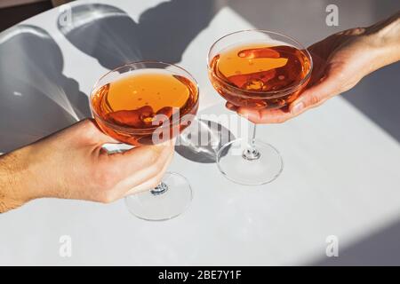 Close up view of man and woman hands holding glasses with cocktail of orange color Stock Photo