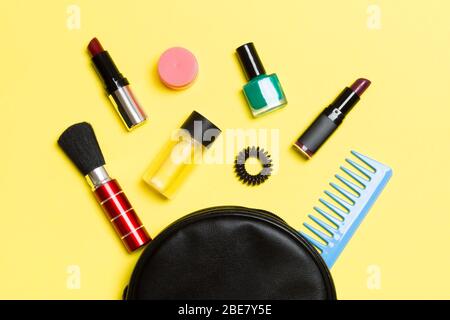 Top view od cosmetics bag with spilled out make up products on yellow background. Beauty concept with empty space for your design. Stock Photo