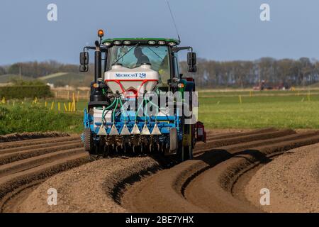 Tarleton UK Weather; 13 Apr 2020.  Dry sunny day for planting seed potatoes in Tarleton. After a cold night with light frost the soils are in fine condition for tilling and forming the deep furrowed grooves, for drainage purposes, to enable the spring planting of farm crops using a Grimm Malpas attachment and a front fertilizer with a John Deere 6135R. Maincrops or Earlies include ‘Maris Piper’ type potatoes, and take 16 to 22 weeks to mature. Seed potatoes are ready to plant when the shoots ‘chit' after they start sprouting   Credit: MediaWorldImages/AlamyLiveNews Stock Photo