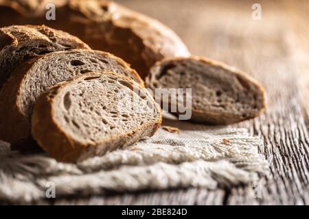 Closeup of fresh slices of organic homemade bread loafs on a rustic cloth and wooden table. Stock Photo