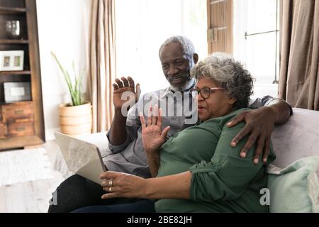 A senior African American couple waving at the laptop and smiling