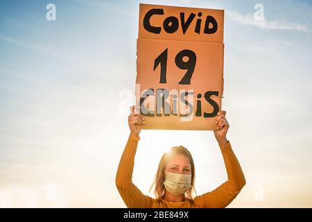 Millennial girl protest for Covid !9 economic crisis - Womand demonstrator wearing surgical mas for coronavirus prevention - Focus on banner Stock Photo