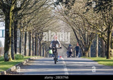 Pictured: A man cycles on the seaside path in Swansea, Wales, UK. Friday 27 March 2020 Re: Covid-19 Coronavirus pandemic, UK. Stock Photo