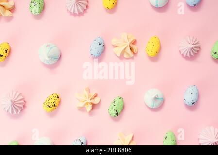 Pastel-colored quail eggs and meringues pattern. Sweet candy for Easter and decorative little eggs on a pink background. Stock Photo