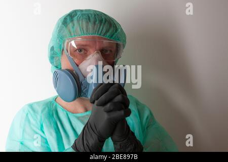 Male nurse, with twin filter half face respirator mask , protective eyglasses,  cap, gown,  with  personal protective equipment to protect against the Stock Photo