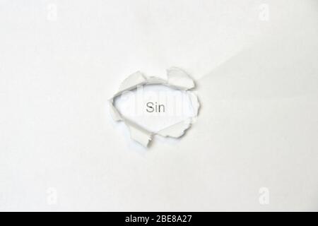 Word sin on white isolated background, the inscription through the wound hole in the paper. Stock photo for web and print with empty space for text and design. Stock Photo