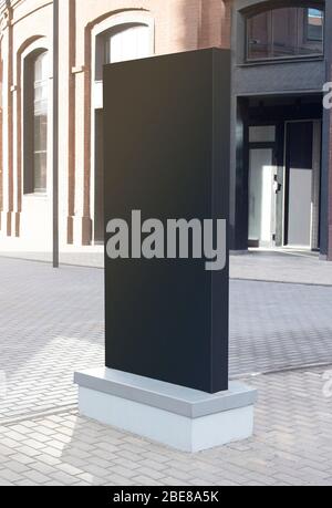 Blank black vertical pylon stand mockup brick building, side view Stock Photo