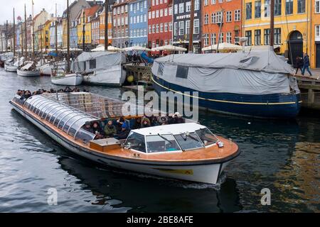 Wide and flat bottomed tour boats take visitors along the canals along Nyhavn in Copenhagen, Denmark Stock Photo