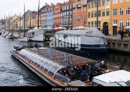 Wide and flat bottomed tour boats take visitors along the canals along Nyhavn in Copenhagen, Denmark Stock Photo