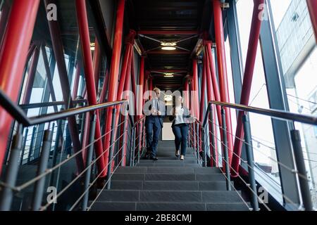 low angle view of businessman and asian businesswoman walking on stairs Stock Photo