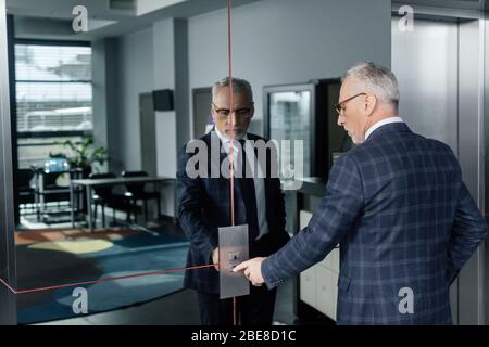 businessman in formal wear pushing button of elevator Stock Photo