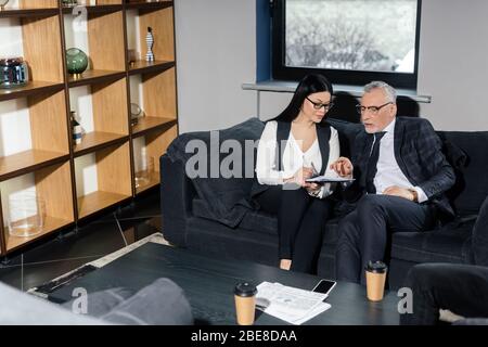 businessman in suit and asian businesswoman talking and holding papers Stock Photo