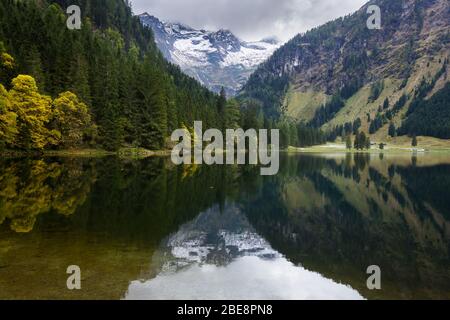 Beautiful alpine lake with reflection and surrounded by mountains covered in snow Stock Photo
