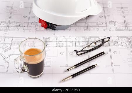 Architects workplace - architectural blueprints with safety helmet, glasses, propelling pencil and coffee on table. Top view. Stock Photo