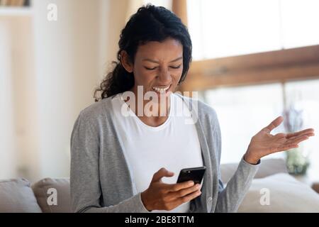 Angry african girl look at smartphone screen Stock Photo