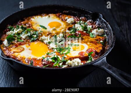 Shakshouka - Middle eastern traditional dish with poached eggs in tomato sauce with feta cheese