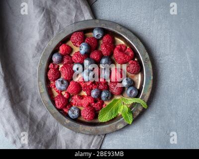 Blueberries and raspberries on plate. A mix of berries on dark background Stock Photo
