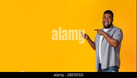Great offer. Joyful black guy pointing aside at copy space Stock Photo