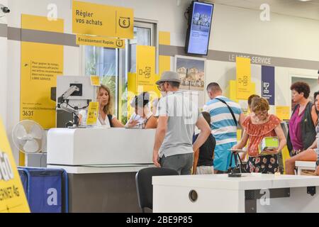 CAP D'AGDE, FRANCE - JULY 27, 2016: People stand in a queue for post office services. Sending parcel. Stock Photo
