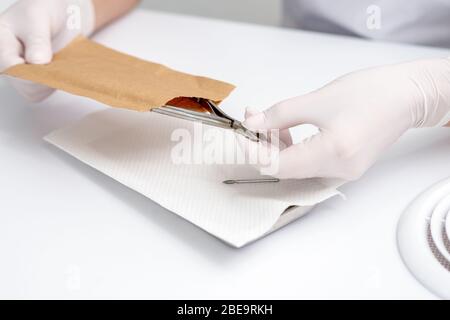 Hands taking manicure tools from craft envelope before manicure procedure. Stock Photo