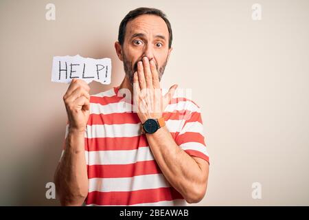 Middle age hoary man holding paper with help message over isolated white background cover mouth with hand shocked with shame for mistake, expression o Stock Photo