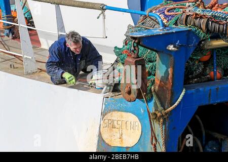 Troon, Ayrshire, UK. 13th Apr, 2020. Coronavirus lock down is affecting the Scottish fishing fleet with all fish markets closed and all fishing boats and trawlers berthed for an indefinite period and that means the fishing crews have no regular income. Here, a fisherman spends his Easter Sunday maintaining his boat at a time when he would be expecting to be at sea. Credit: Findlay/Alamy Live News Stock Photo